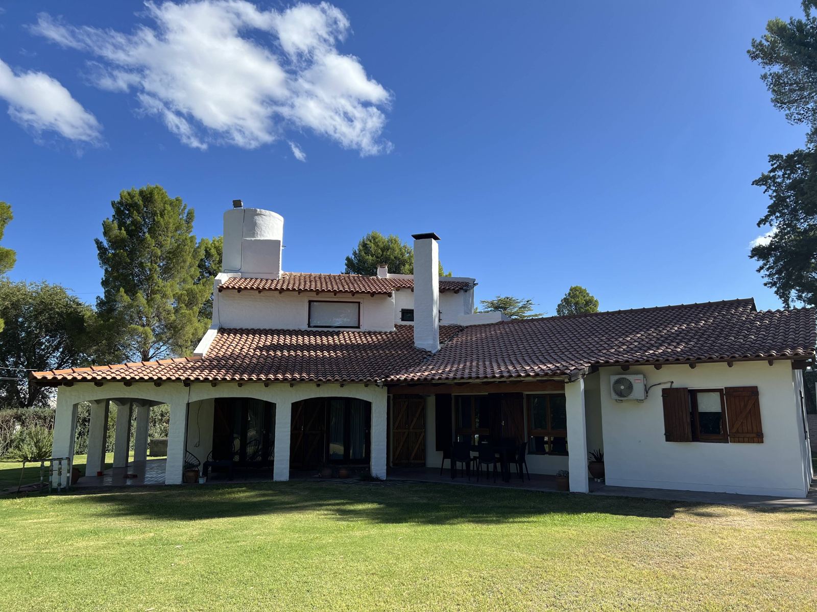 Frente de la casa con galería de arcos y parque